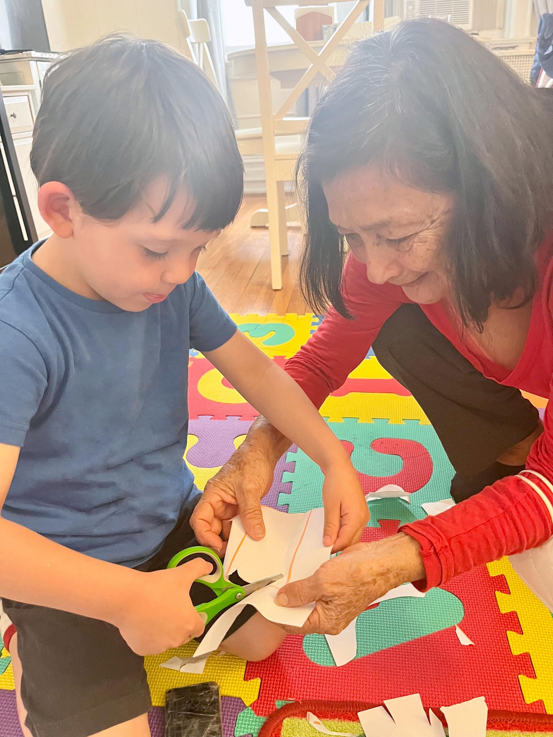Boy cutting paper with his grandmother